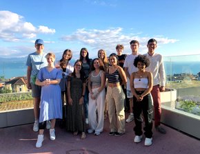 Un groupe de jeunes personnes sur une terrasse, sur fond de lac et de vignes