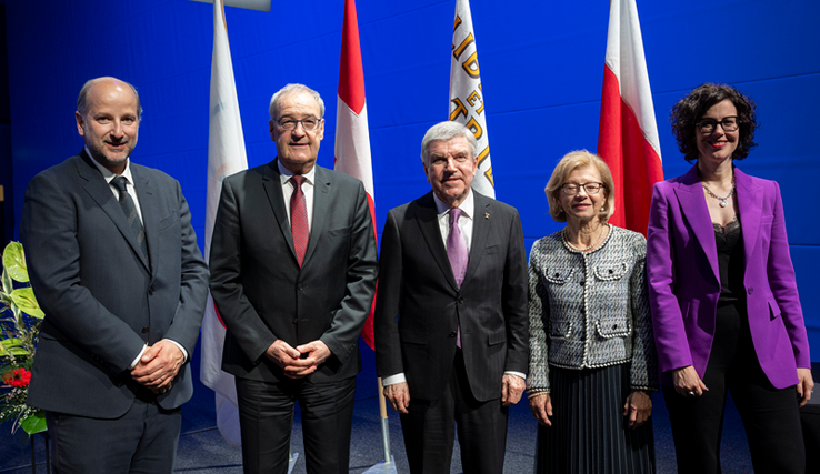 Les personnages posent côte à côte; derrière eux, des drapeaux.