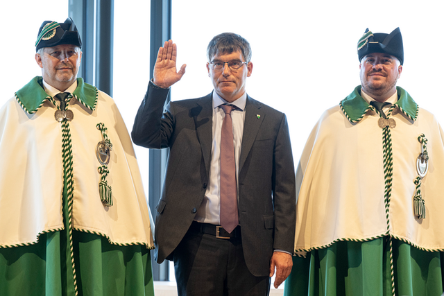 Il lève la main lors de la prestation, entre deux huissiers en grande tenue.