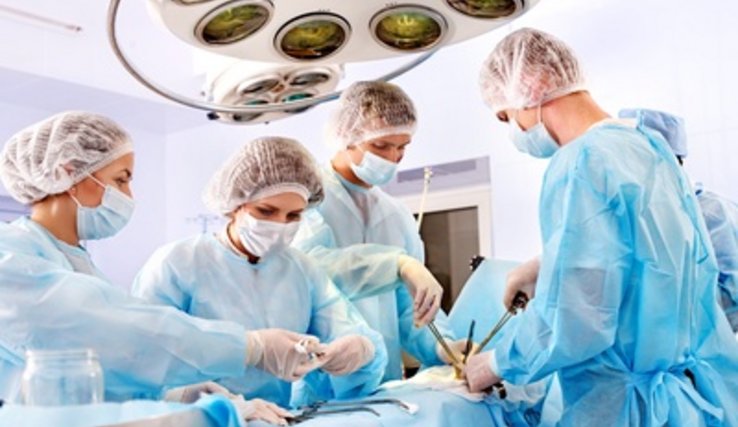 Vue d'une salle d'opération: personnel médical en tenue chirurgicale au travail autour de la table d'opération.