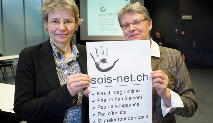 Les deux ministres, debout, tiennent une affiche de la campagne sur laquelle on lit en gros "soit-net.ch".
