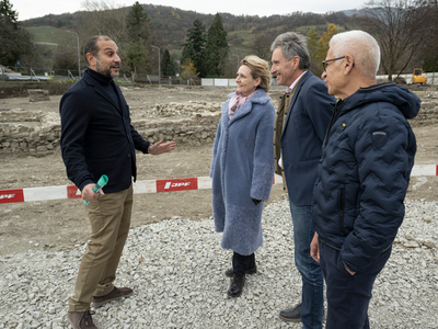 Les personnes écoutent l'archéologue cantonal. On voit à leurs coiffures que le vent souffle.