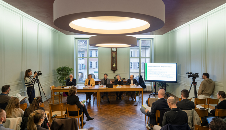 conférence de presse dans une salle de l'Hôtel de Ville d'Orbe. Les orateurs et oratrices sont au fond derrière une table. Les représentants des médias sont de dos.