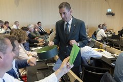 Un huissier en train de collecter les bulletins de vote dans l'assemblée.