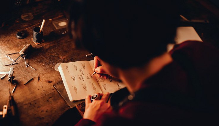 Morgane Meylan, bijoutière, dessine l'esquisse d'un bijoux sur un cahier dans son atelier de Lausanne.